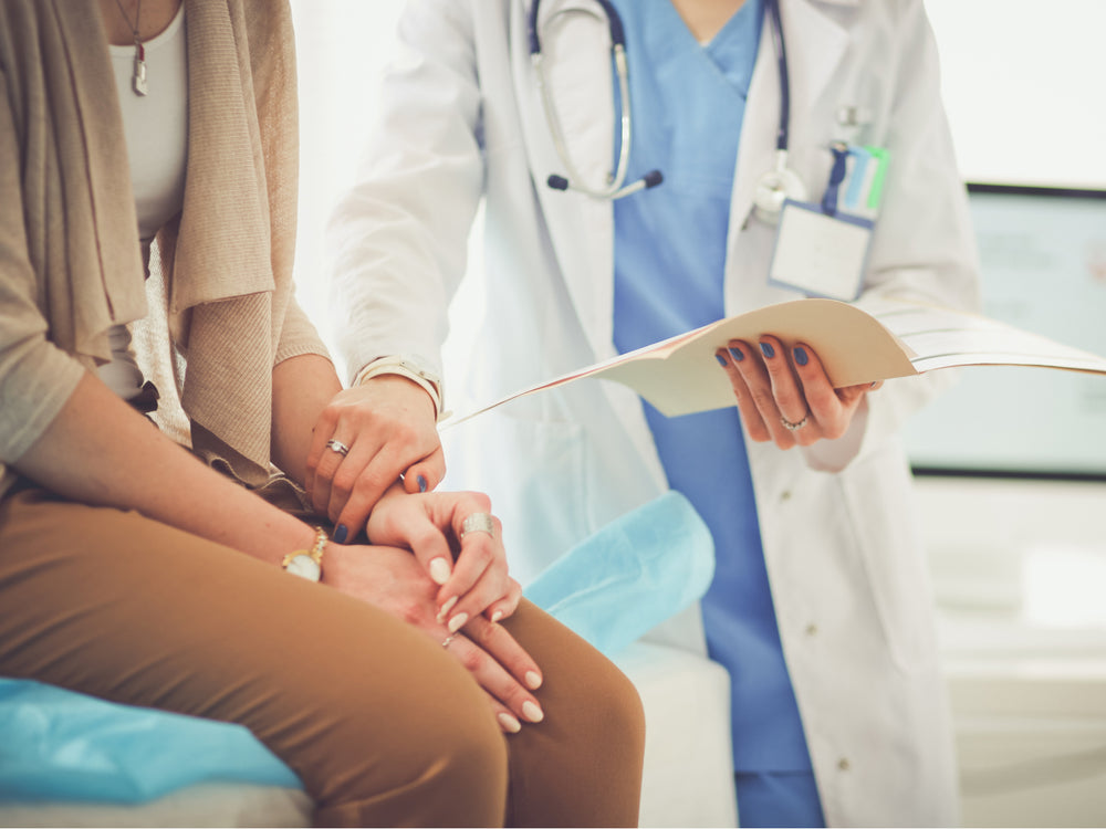 Doctor holding a piece of paper while sitting with a patient, indicating a consultation or discussion.